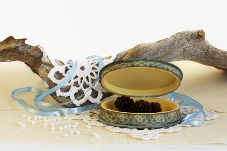 open oval wooden box of hand work, yellow and blue. Dry root of the tree, white knitted napkins, dry hydrangea and cones of larchの写真素材