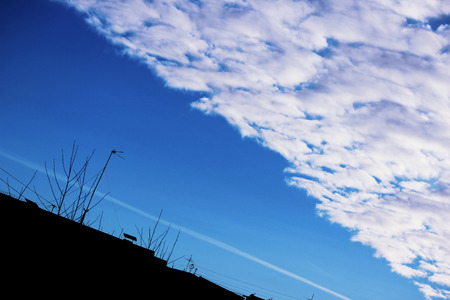 The boundary of cirrus clouds in the bright blue sky and the city houseの写真素材