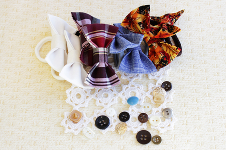 many small butterflies made of fabric on hair elastic bands to create a hairstyle on the head, on a white delicate napkin, on a beige backgroundの写真素材