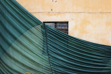 partially fallen building mesh with wrinkles, protecting the old house with a plastered wall.の写真素材