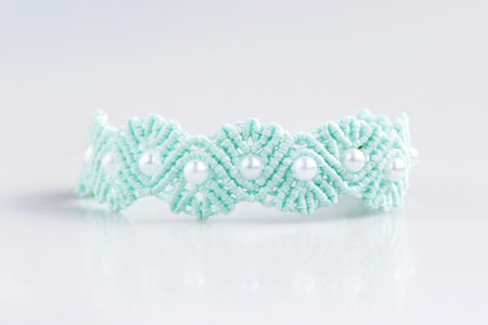 turquoise and blue braceletes with white beads for the hand from waxed thread in the technique of macrame on a white backgroundの写真素材