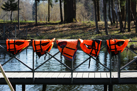 five orange lifejackets hang on the railing near the pier at the boat station. Gatchina, Russiaの写真素材