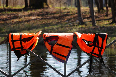 three orange lifejackets hang on the railing near the pier at the boat station. Gatchina, Russiaの写真素材