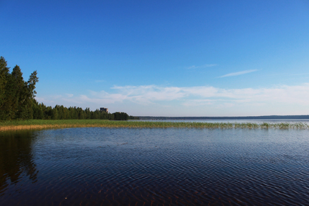 Lake Vysokinskoye in the summer, with the reflection of white clouds in the water. Leningrad Region, Russiaの写真素材