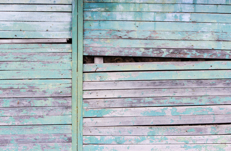 Vintage wood background with peeling turquoise old flaky paint. Slanting slit in the wall of a large barn due to skewed boardsの写真素材