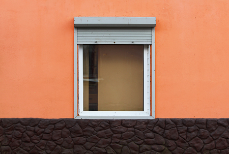 One window in the house is half closed by external shutters. bright orange and brown color of the plaster.の写真素材