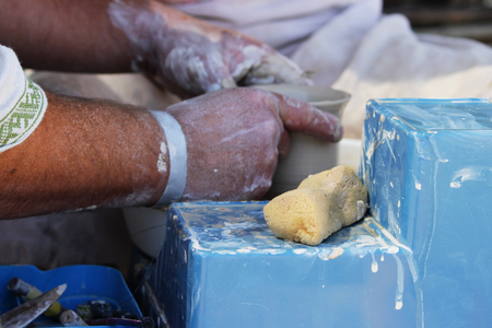 an experienced master potter teaches a young girl to turn a pot of clay on a potter's wheel. reportage shootingの写真素材