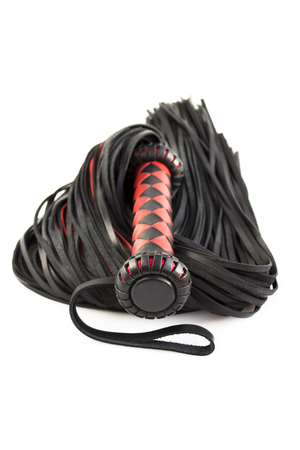 Red-black floger with a patterned handle and leather tails. vertical photo on white background.concept of pleasure from pain.の写真素材
