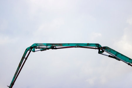 The device of a turquoise loader on the railway. Hydraulic system against the sky.