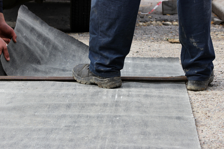 emergency water service team cuts pieces of roofing material for wrapping the water pipe at the accident site for thermal insulation. reportage photography, Russiaの写真素材