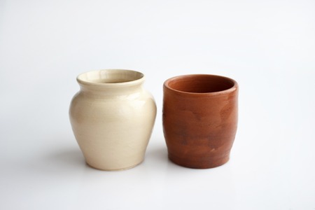 Clay pot and glass, made by hand on a potter's wheel from red and white clay. Double burning. Transparent glaze applied by hand - visible potter's fingerprints and brush strokes. Handmade, single copy. White background.の写真素材