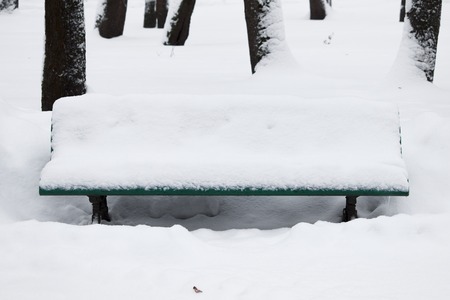 Winter landscape with snowfall and snowdrifts. snow removal in Gatchina Park. bench covered with snowの写真素材