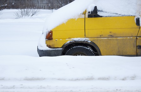 problem after snowfall - snow on the city road, snow porridge. yellow car with wheels covered with snow. problem for snow removal equipment. Gatchina, Russiaの写真素材