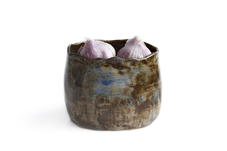 cup on a white background. It is molded manually of clay, covered with two layers of glaze - blue and black. used to store garlic. uneven glazingの写真素材