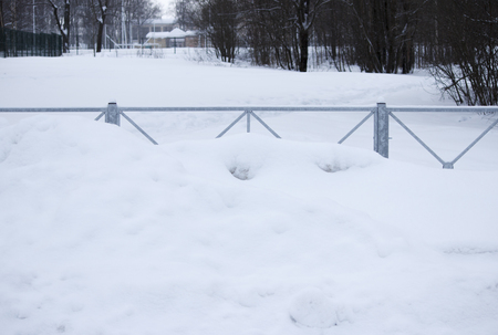 problem after snowfall - snow on the city road, snow porridge. fence covered with snow at the parking lot.の写真素材