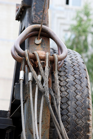 Hydraulic system. The device metal rings attached with steel cables to the yellow loader and spare rubber tire on the side. reporting shootingの写真素材