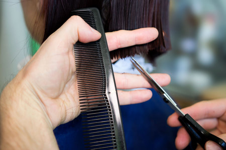 Redhead young woman getting haircut by man hairdresser, which does a bob hairstyle before dyeingの写真素材