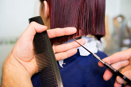 Redhead young woman getting haircut by man hairdresser, which does a bob hairstyle after dyeingの写真素材