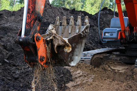 the excavator draws water from the ditch with a bucket where the road will pass. rain season. repair and expansion of the road. storm concrete rings. Gatchina, Russia, reportageの写真素材