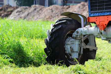tractor that mows grass on urban lawns. the tractor mows the grass with a special attachment mower with circular knives. front wheel close upの写真素材