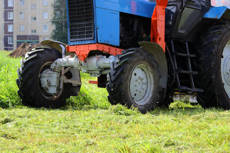 tractor that mows grass on urban lawns. the tractor mows the grass with a special attachment mower with circular knives. wheels close upの写真素材