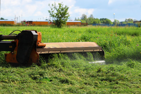 nozzle on a tractor that mows grass on urban lawns. the tractor mows the grass with a special attachment mower with circular knivesの写真素材