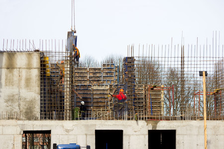 the worker and the crane operator unload the car with reinforced concrete walls for building a large wellness center with a swimming pool of modern technology with concrete poured reinforced and formwork walls. reportage.の写真素材