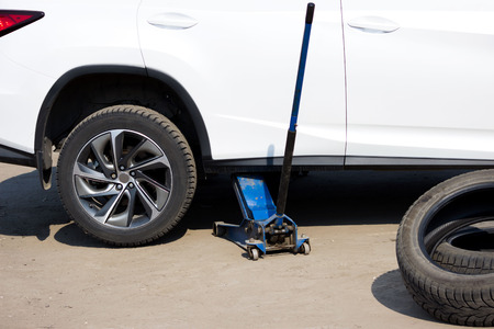 spring tire fitting. Replacing studded wheels with ordinary ones. The jack on the other hand lifts the car and the wheel is removed thereの写真素材