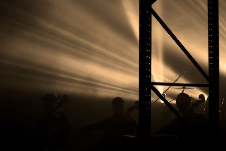 reportage of the group consisting of four cellists and a drummer on the stage lit by a sepia light from behind.の写真素材