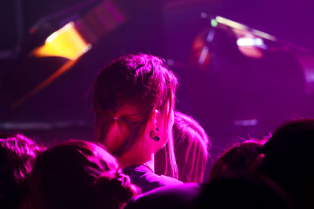 spectators in the forefront at a live concert of the group consisting of four cellists and a drummer. The scene is lit with purple spotlights.の写真素材