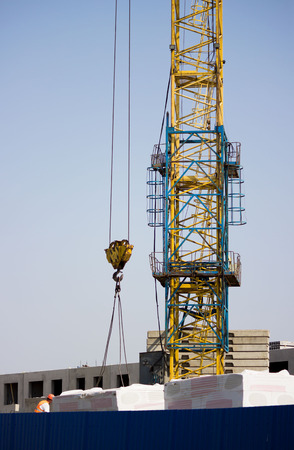 the worker and the crane operator unload the car with reinforced concrete walls for the future high-rise building. reportage shooting.の写真素材
