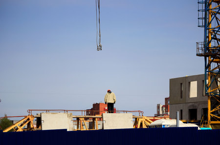 the worker and the crane operator unload the car with reinforced concrete walls for the future high-rise building. reportage shooting.の写真素材