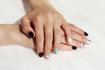 hands of a young girl with green, black and white manicure, with stickers.の写真素材