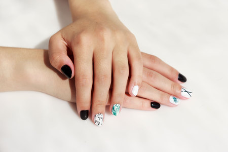 hands of a young girl with green, black and white manicure, with stickers.の写真素材