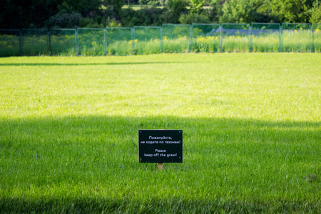 warning label on the meadow Gatchina park. Inscriptions in Russian and English: please do not walk...