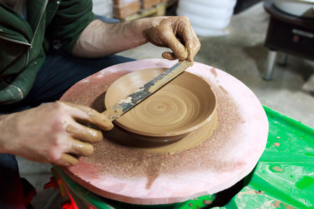 the master measures with a ruler the width of the plate, made to order from red clay. The product is made on a potter's wheel, on a sheet of chipboard for better removal and further drying. reportageの写真素材