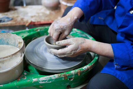 A novice student in the first lesson in pottery tries to make a product from clay on a potter's wheel. reportageの写真素材