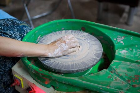 A novice student in the first lesson in pottery tries to make a product from clay on a potter's wheel. reportageの写真素材