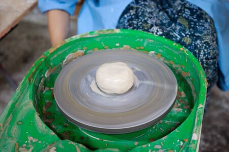 A novice student in the first lesson in pottery tries to make a product from clay on a potters wheel. reportageの写真素材