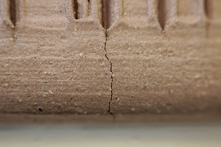 side wall of a red clay pot with vertical stripes made for decoration and texture. dried and unburned product. macro. pottery ceramic art. crack due to fast drying and too deep furrows due to texture decorationの写真素材
