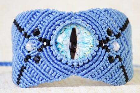 blue bracelete with white beads and the dragons eye on the hand from waxed thread in the technique of macrame. Handmade.の写真素材