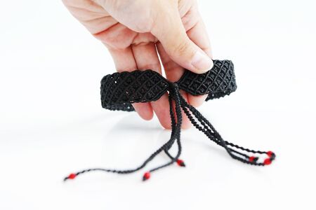 black choker with red dragon's eye for neck from waxed thread in the technique of macrame on a white background. Handmade. Concept bdsm.の写真素材