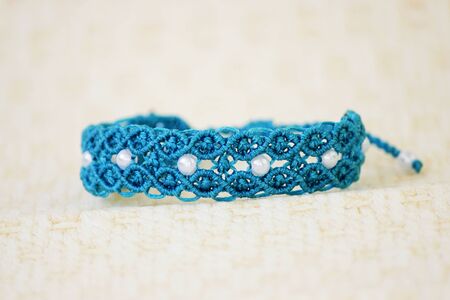 turquoise bracelete with white beads for the hand from waxed thread in the technique of macrame. Handmadeの写真素材