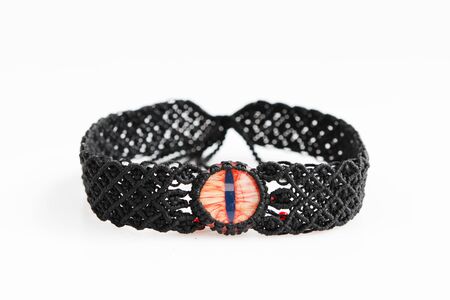 black choker with red dragon's eye for neck from waxed thread in the technique of macrame on a white background. Handmade. Concept bdsm.の写真素材