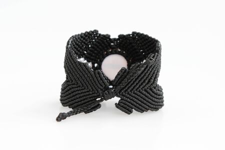 black bracelete with red dragon's eye for arm from waxed thread in the technique of macrame on a white background. Handmade.の写真素材