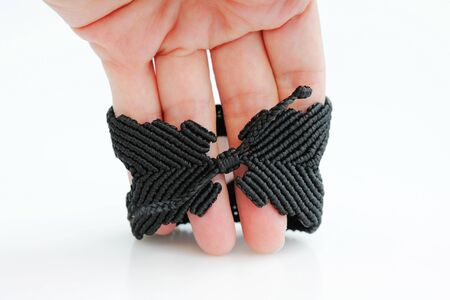 black bracelete with red dragon's eye for arm from waxed thread in the technique of macrame on a white background. Handmade.の写真素材