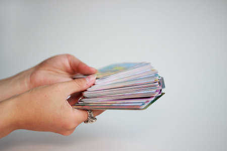 fortune-tellers' hands hold a deck of tarot cards on a gold background.