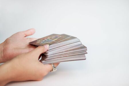 fortune-tellers' hands hold a deck of tarot cards on a gold background.の写真素材