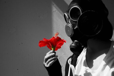 girl in gas mask with a red flower in her hand. cosplay, black and whiteの写真素材