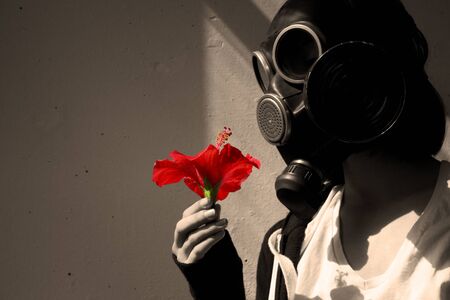 girl in gas mask with a red flower in her hand. cosplay, sepiaの写真素材